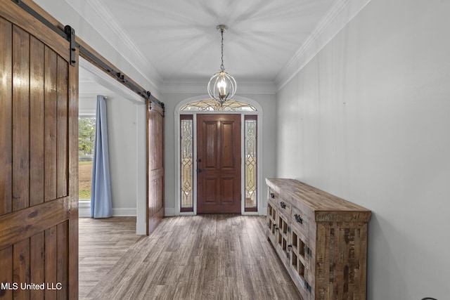 foyer entrance featuring ornamental molding, wood finished floors, and a barn door