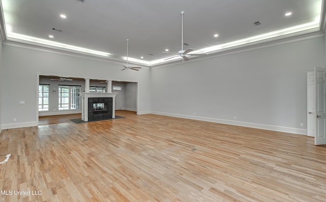 121 Poplar Ridge Dr, Brandon, MS 39047 - unfurnished living room featuring ceiling fan, a tray ceiling, light wood-style floors, baseboards, and a tiled fireplace