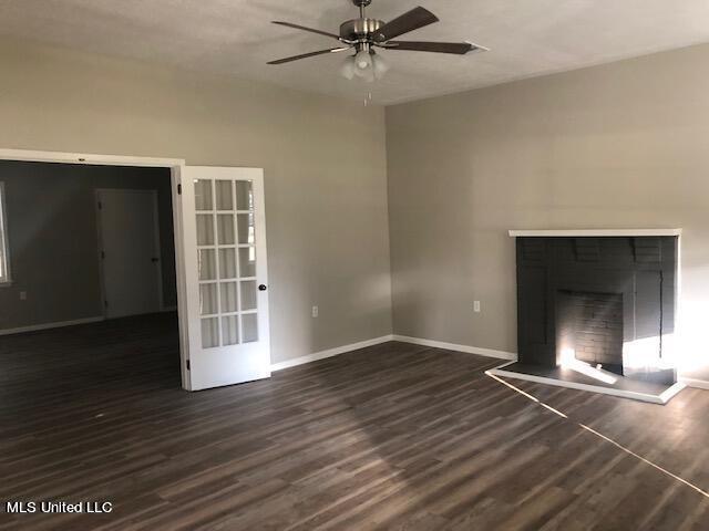 unfurnished living room with french doors, ceiling fan, a fireplace, and dark hardwood / wood-style floors