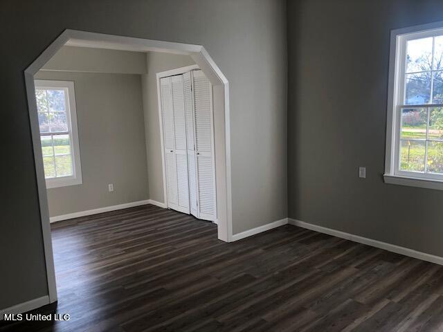 unfurnished bedroom featuring a closet and dark wood-type flooring