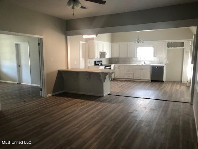 kitchen with decorative backsplash, white cabinetry, a kitchen bar, kitchen peninsula, and stainless steel appliances