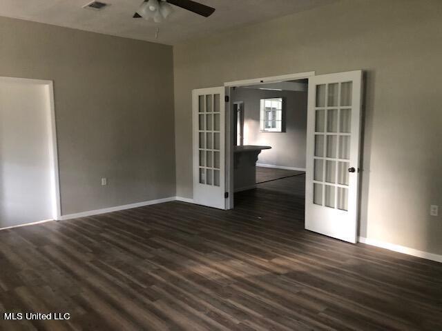 empty room featuring ceiling fan, dark wood-type flooring, and french doors