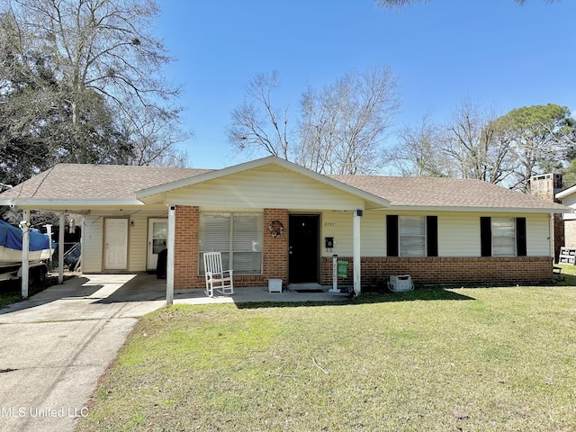 single story home featuring brick siding, a shingled roof, concrete driveway, a front yard, and an attached carport