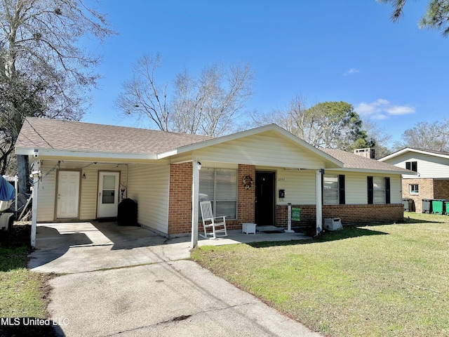 view of front of property with brick siding, a shingled roof, concrete driveway, a front yard, and a carport