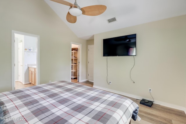 unfurnished bedroom featuring light wood finished floors, baseboards, high vaulted ceiling, a spacious closet, and a ceiling fan
