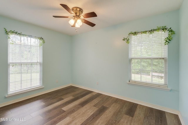 spare room with dark wood-style floors, healthy amount of natural light, and baseboards