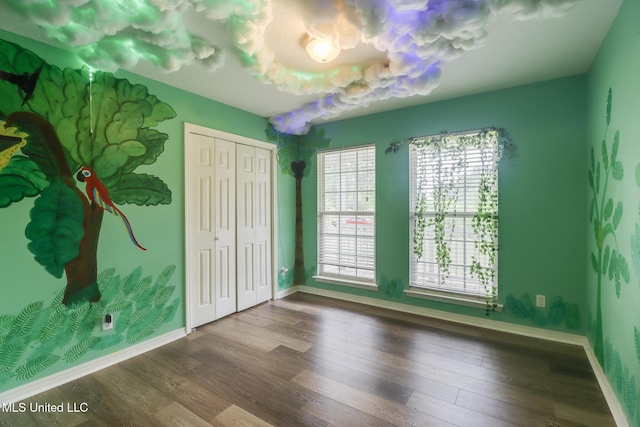 unfurnished bedroom with baseboards, wood finished floors, and a closet