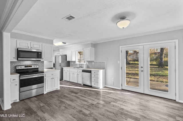 kitchen with stainless steel appliances, light countertops, visible vents, and wood finished floors