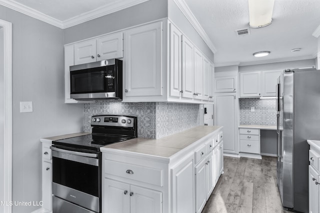 kitchen with crown molding, visible vents, appliances with stainless steel finishes, white cabinets, and light wood-type flooring