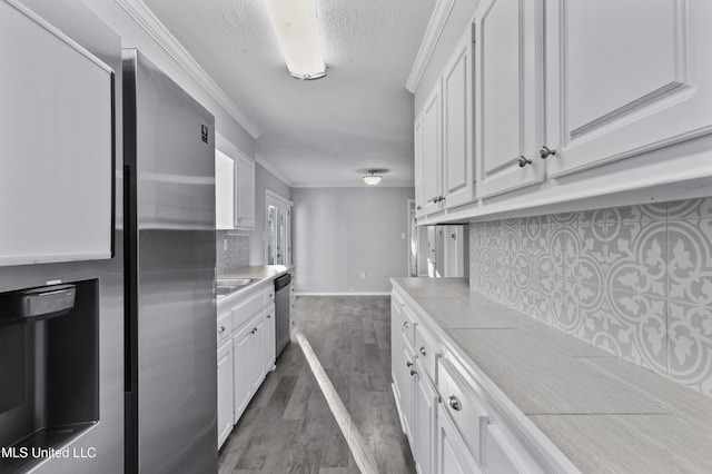 kitchen featuring stainless steel appliances, light countertops, backsplash, white cabinetry, and wood finished floors