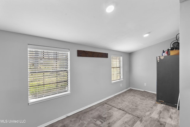 spare room with baseboards and wood finished floors