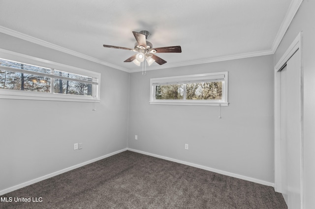 unfurnished bedroom featuring a ceiling fan, baseboards, a closet, dark carpet, and crown molding