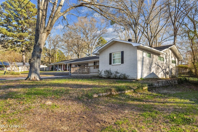 view of side of property with a yard, brick siding, and a chimney