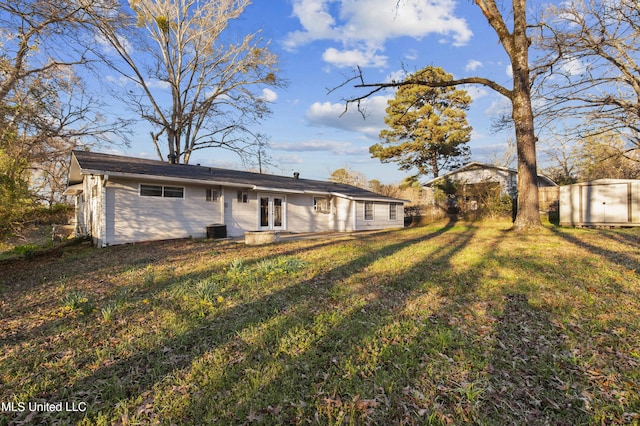 rear view of property with french doors, a storage unit, central air condition unit, a lawn, and an outdoor structure