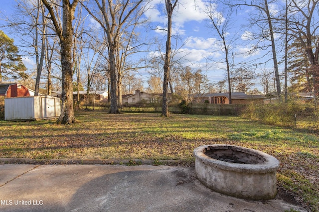 view of yard with a storage unit, fence, a fire pit, and an outdoor structure