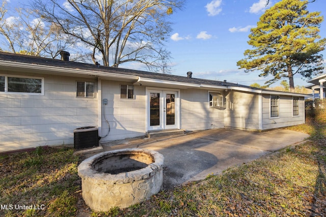 rear view of property with central air condition unit, a fire pit, french doors, and a patio