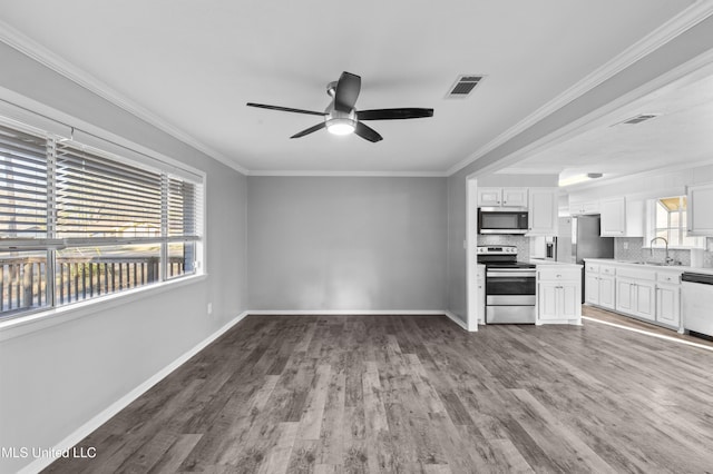 unfurnished living room featuring ornamental molding, wood finished floors, visible vents, and a healthy amount of sunlight