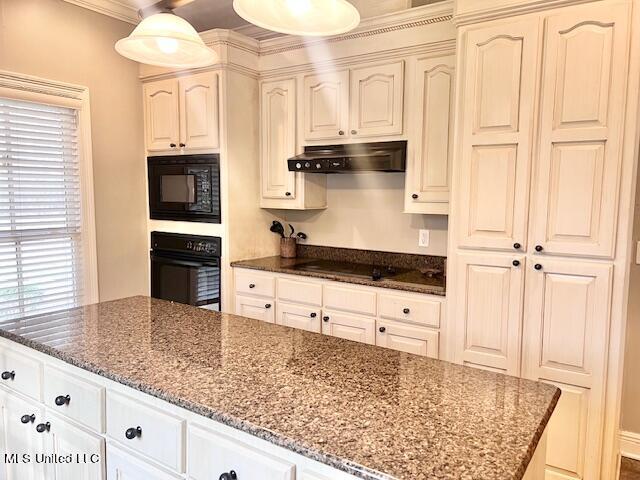 kitchen featuring pendant lighting, black appliances, dark stone counters, and a center island