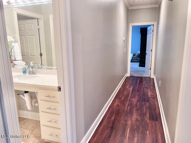 hall with crown molding, sink, and hardwood / wood-style flooring