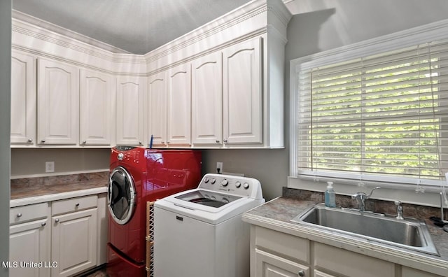 clothes washing area featuring cabinets, sink, and washer and clothes dryer