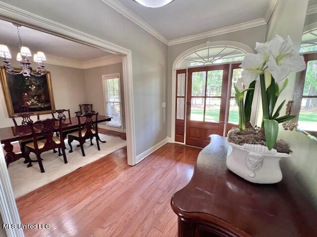 doorway to outside featuring hardwood / wood-style flooring, ornamental molding, and an inviting chandelier