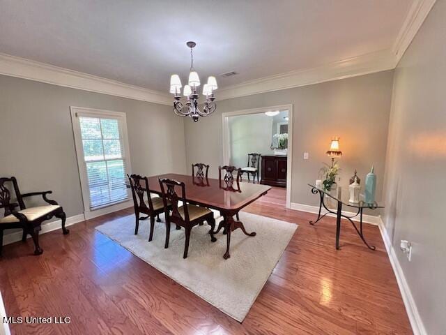 dining space with hardwood / wood-style flooring, ornamental molding, and a chandelier