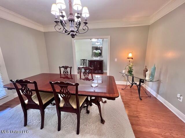 dining space with ornamental molding, a chandelier, and light hardwood / wood-style floors