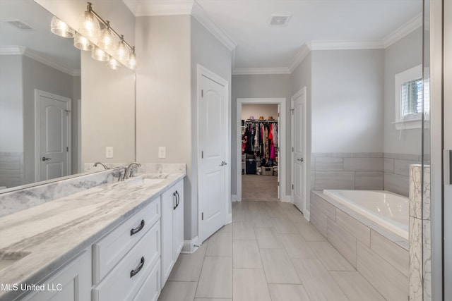 bathroom with vanity, a spacious closet, a garden tub, and visible vents