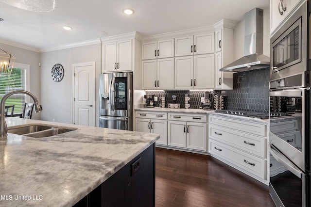 kitchen with a sink, wall chimney range hood, stainless steel appliances, tasteful backsplash, and dark wood-style floors