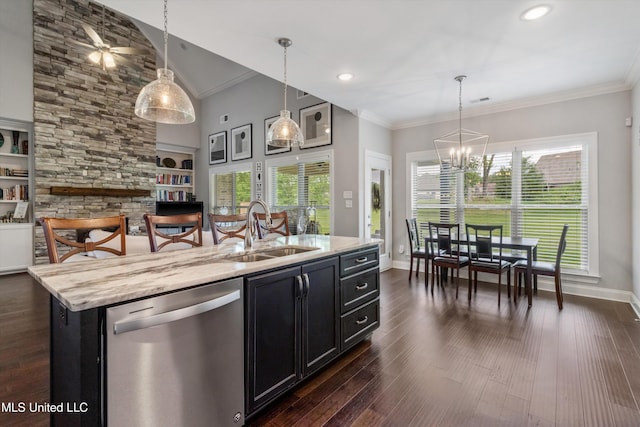 kitchen with stainless steel dishwasher, dark cabinetry, pendant lighting, and a sink