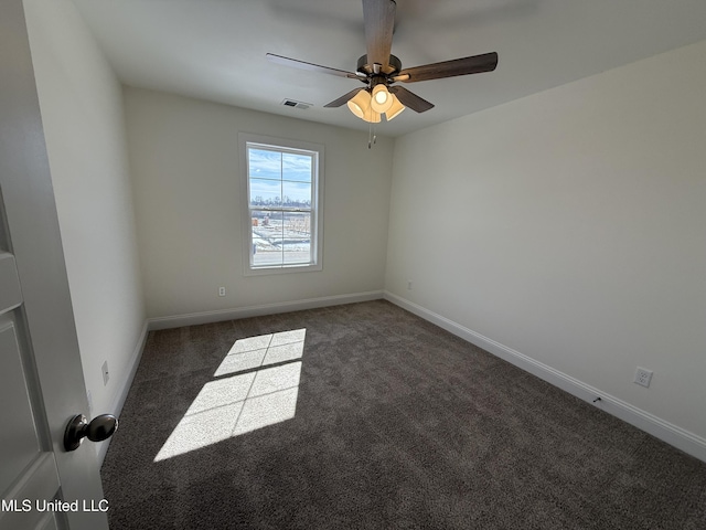 spare room with ceiling fan, dark colored carpet, visible vents, and baseboards