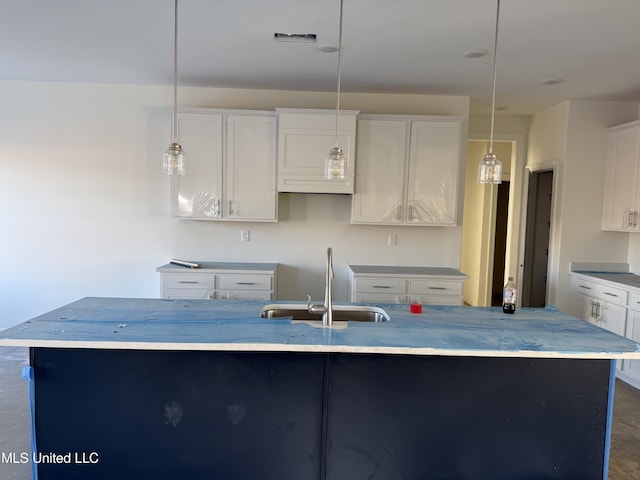 kitchen featuring light countertops, pendant lighting, a kitchen island with sink, and a sink