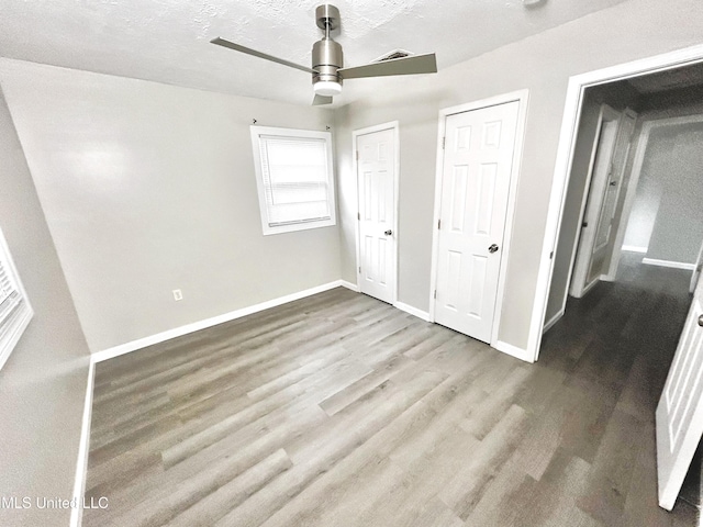 unfurnished bedroom featuring ceiling fan, a textured ceiling, and wood-type flooring