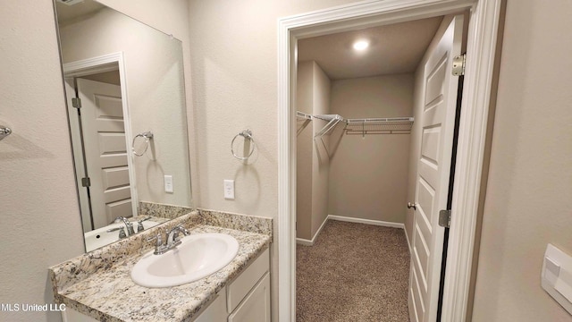 bathroom with vanity, baseboards, and a spacious closet