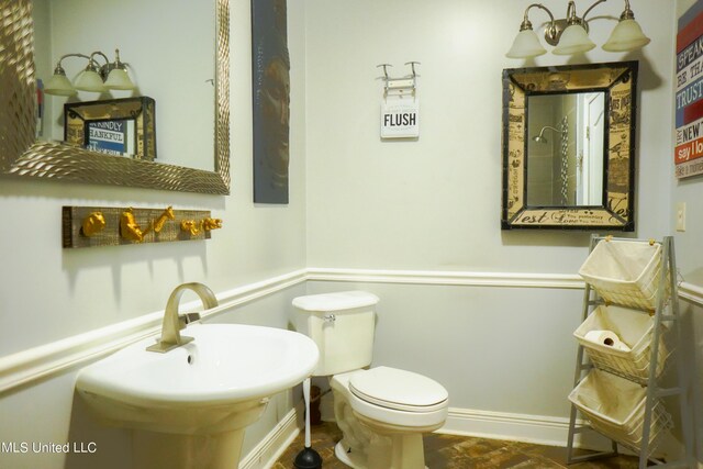 bathroom with toilet, a sink, and baseboards