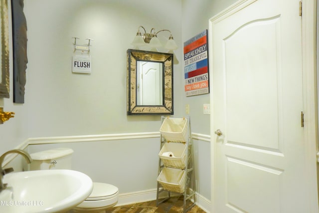 bathroom with toilet, baseboards, and a sink