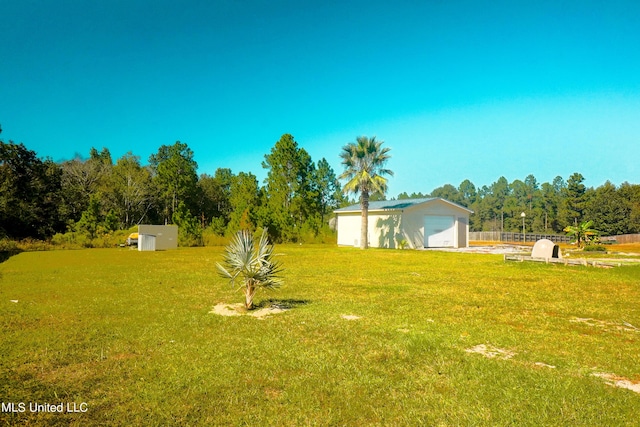 view of yard with fence, an outbuilding, and a garage