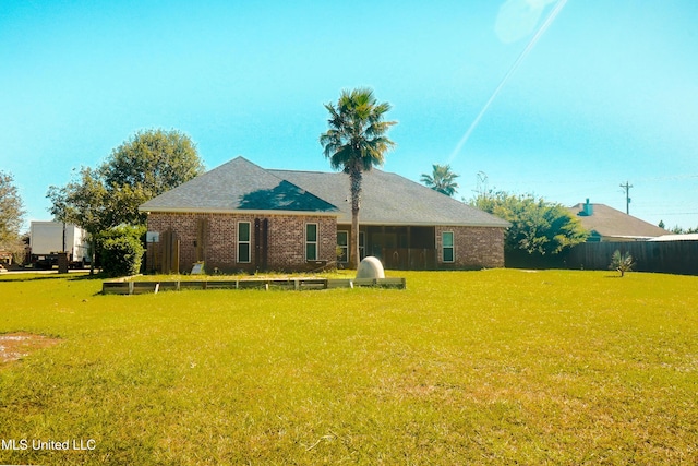 back of house featuring fence, brick siding, and a yard
