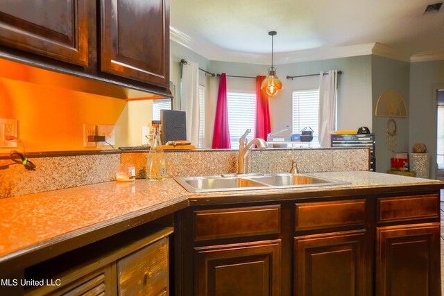 kitchen featuring crown molding, hanging light fixtures, a sink, light countertops, and visible vents