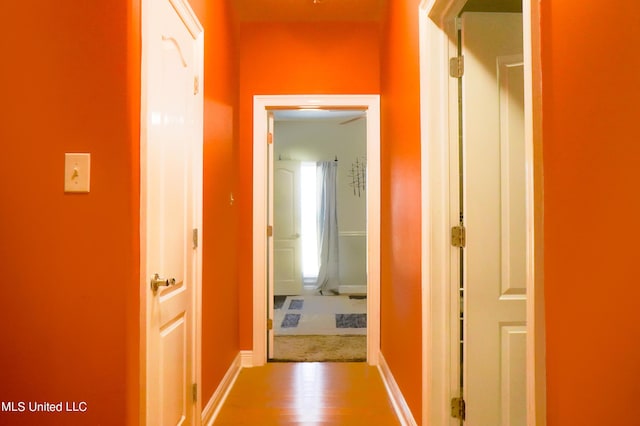 corridor featuring wood finished floors and baseboards