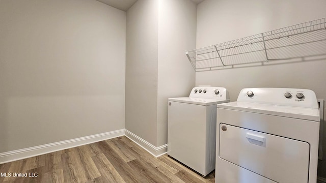 laundry area with washing machine and clothes dryer and light hardwood / wood-style flooring