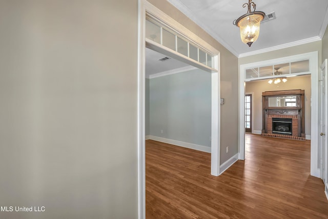 hallway with baseboards, wood finished floors, visible vents, and ornamental molding