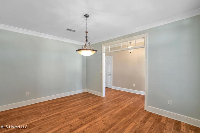 unfurnished room featuring visible vents, baseboards, wood finished floors, and crown molding