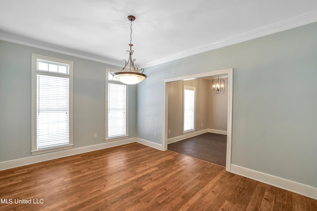 spare room featuring baseboards, an inviting chandelier, dark wood-style flooring, and crown molding