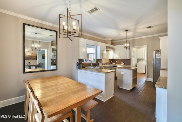 kitchen with visible vents, a sink, washer / clothes dryer, an inviting chandelier, and appliances with stainless steel finishes