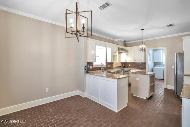 kitchen with baseboards, washer / dryer, open shelves, appliances with stainless steel finishes, and a notable chandelier