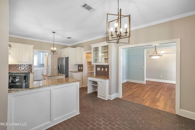 kitchen featuring visible vents, a notable chandelier, stainless steel fridge with ice dispenser, baseboards, and washer / dryer