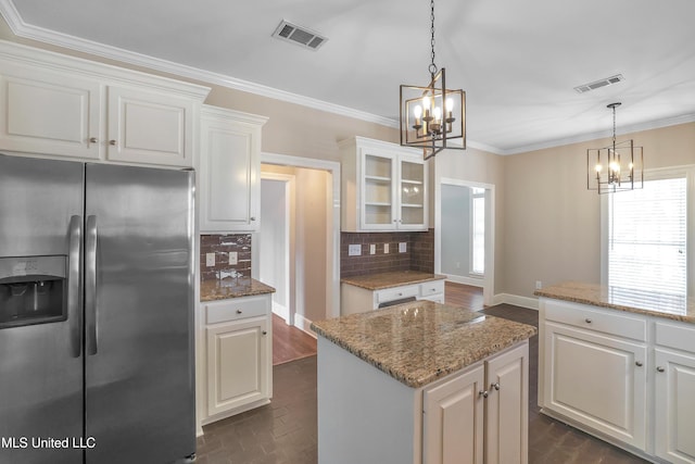 kitchen with visible vents, stainless steel fridge, backsplash, and a chandelier