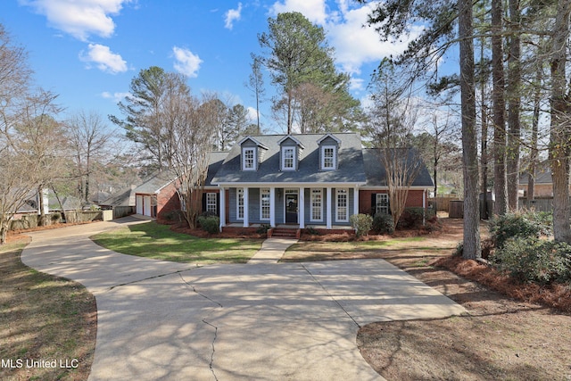 cape cod home with fence, driveway, a porch, a garage, and brick siding