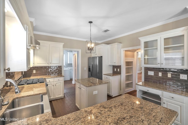 kitchen with visible vents, a sink, a kitchen island, stainless steel fridge with ice dispenser, and washing machine and clothes dryer